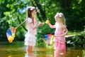 Two cute little sisters playing in a river catching rubber ducks with their scoop-nets Royalty Free Stock Photo