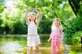 Two cute little sisters playing in a river catching rubber ducks with their scoop-nets Royalty Free Stock Photo