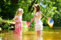 Two cute little sisters playing in a river catching rubber ducks with their scoop-nets on warm and sunny summer day Royalty Free Stock Photo