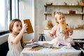 Two cute little sisters preparing cookies at home kitchen