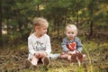 Two cute little sisters sitting in the summer forest. Royalty Free Stock Photo