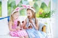 Two cute little sisters wearing bunny ears eating chocolate Easter rabbits Royalty Free Stock Photo