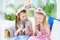 Two cute little sisters wearing bunny ears eating chocolate Easter rabbits Royalty Free Stock Photo