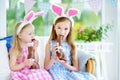 Two cute little sisters wearing bunny ears eating chocolate Easter rabbits Royalty Free Stock Photo
