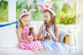 Two cute little sisters wearing bunny ears eating chocolate Easter rabbits. Kids playing egg hunt on Easter. Children celebrate Ea Royalty Free Stock Photo