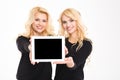 Two cute lovely sisters twins showing blank tablet computer screen Royalty Free Stock Photo