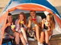 Students eating noodles near the tent on a natural background. Couples on a camping trip. Travelling and hiking concept.
