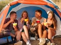 Students eating noodles near the tent on a natural background. Couples on a camping trip. Travelling and hiking concept.