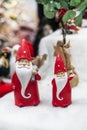 two cute Santa Clauses in red caps with gifts in the snow.