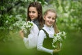 Two cute schoolgirl girls in an apple blossoming garden after school. End of school year