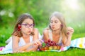 Two cute sisters or friends in a picnic garden lie on a deck and eat freshly picked cherries Royalty Free Stock Photo