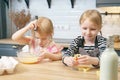 Two cute sisters preparing cookie dough. Little girls helping mom in the kitchen