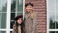 Two cute smiling girls in berets standing together outdoor