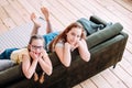 Two cute smiling girls children friends tweens sitting on sofa at home