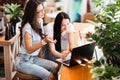 Two cute smiling slim girls with long dark hair,wearing casual style,sit at the table and look attentively at the laptop Royalty Free Stock Photo