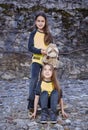 Two cute teenage females with skateboard and plushy toy.