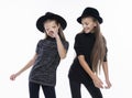 Two cute teenage girlfriends schoolgirls wearing turtleneck sweaters, jeans and hats, smiling dancing.  on white. Fashion Royalty Free Stock Photo