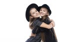 Two cute teenage girlfriends schoolgirls wearing turtleneck sweaters, jeans and hats, smiling hug each other. Isolated on white. Royalty Free Stock Photo