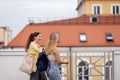 Two cute teenage girls chat and walk together. Funny students in casual clothes with backpacks talking and laughing on the roof of