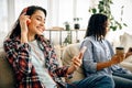 Two cute women in headphones leisures on sofa Royalty Free Stock Photo