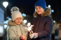 Two cute young children, boy and girl in warm winter clothing holding burning sparkler fireworks on dark night outdoors bokeh Royalty Free Stock Photo