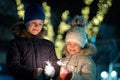 Two cute young children, boy and girl in warm winter clothing holding burning sparkler fireworks on dark night outdoors bokeh Royalty Free Stock Photo