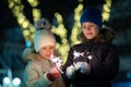 Two cute young children, boy and girl in warm winter clothing holding burning sparkler fireworks on dark night outdoors bokeh Royalty Free Stock Photo