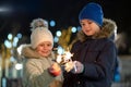 Two cute young children, boy and girl in warm winter clothing holding burning sparkler fireworks on dark night outdoors bokeh Royalty Free Stock Photo