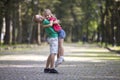 Two cute young funny smiling children, girl and boy, brother holding sister in his arms, having fun on blurred bright sunny park Royalty Free Stock Photo