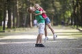 Two cute young funny smiling children, girl and boy, brother holding sister in his arms, having fun on blurred bright sunny park Royalty Free Stock Photo