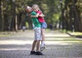 Two cute young funny smiling children, girl and boy, brother holding sister in his arms, having fun on blurred bright sunny park Royalty Free Stock Photo