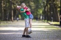 Two cute young funny smiling children, girl and boy, brother holding sister in his arms, having fun on blurred bright sunny park Royalty Free Stock Photo
