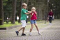 Two cute young laughing children, girl and boy, brother and sister having fun on blurred bright sunny summer park alley green Royalty Free Stock Photo