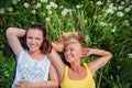 Two cute young women lying in the grass on summer sunny day outdoor. Happy girls enjoy nature.