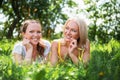 Two cute young women lying in the grass on summer sunny day outdoor. Happy girls enjoy nature.