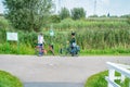 Two cyclists meet on road, one dressed in traditional Dutch costume the other with a red bicycle