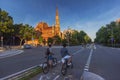 Two cyclists riding in bike lane in Barcelona street with a church on the background Royalty Free Stock Photo