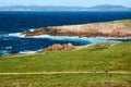 View of two cyclists riding their bikes on path near the Tower of Hercules in CoruÃÂ±a, Spain, surrounded by green grass and