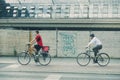 Two cyclists in urban environment, wearing red, the other in business casual attire and shirt, Berlin main station in