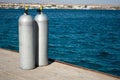 Two cylinders with oxygen. two steel cylinders at sea dock. Full oxygen tanks on pier. Blue water and white aluminum cylinders. Royalty Free Stock Photo