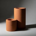 Two cylindrical terracotta objects are displayed against a gray background Royalty Free Stock Photo