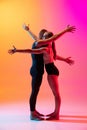 Two dancers, stylish sportive couple, male and female models dancing contemporary dance on colorful gradient yellow pink Royalty Free Stock Photo