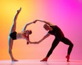 Two dancers, stylish sportive couple, male and female models dancing contemporary dance on colorful gradient yellow pink Royalty Free Stock Photo