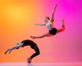 Two dancers, stylish sportive couple, male and female models dancing contemporary dance on colorful gradient yellow pink Royalty Free Stock Photo