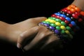 Two dark female hands with a colorful bracelet