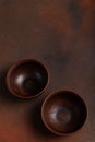 Two dark handmade clay bowls on brown background