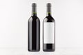 Two dark wine bottles with blank white label and without label, on white wooden board, mock up. Royalty Free Stock Photo