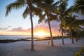 Two deck chairs under palm trees at sunset on an empty beach at Royalty Free Stock Photo