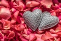 Two decorative carved hearts at red rose petals background