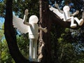 Two decorative street lamps in the form of a sketchy angel are located on a tree in the park